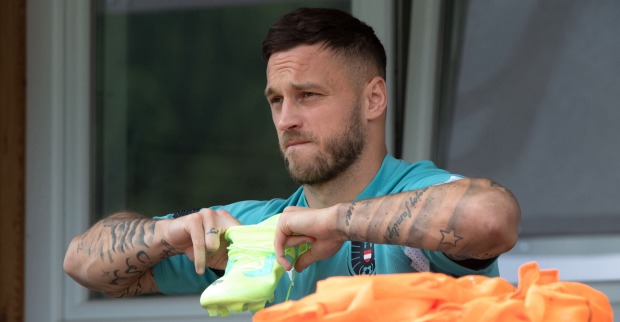 Marko Arnautovic abseits des Spielfelds. Er schaut in die Ferne und hält seinen Schuh vor seiner Brust.