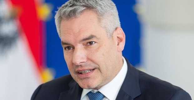 Kanzler Karl Nehammer im Porträt, hinter ihm eine Flagge der Europäischen Union