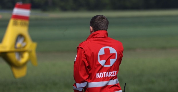 Einen Notarzt, im Hintergrund ein Hubschrauber.