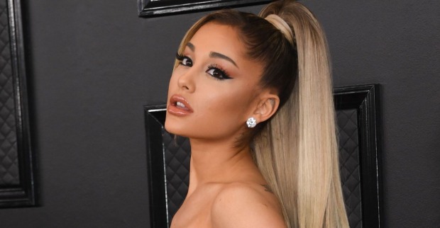 Ariana Grande auf dem roten Teppich vor einer schwarzen Tür mit zusammengebundenen, blonden Haaren.