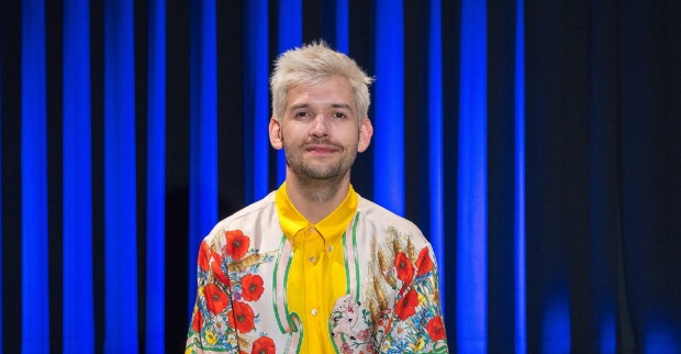 Michael Buchinger in einem bunten Kostüm auf der Kabarettbühne.