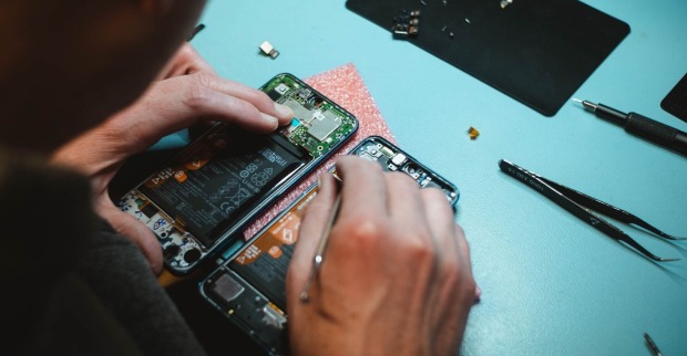 Ein Mann repariert ein aufgeschraubtes Smartphone