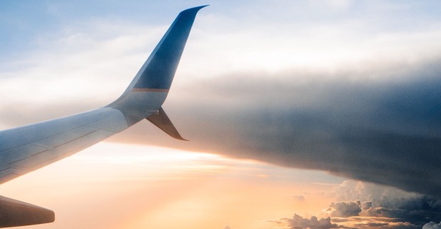 Der Flügel eines Flugzeuges bei Sonnenuntergang im Himmel.