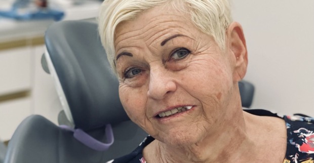 Sängerin Jazz Gitti mit kurzen blonden Haaren und einem Wattebausch im Mund beim Zahnarzt.