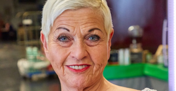 Eine Dame reifen Alters mit einem pinken Lippenstift und sehr kurzen blonden Haaren.