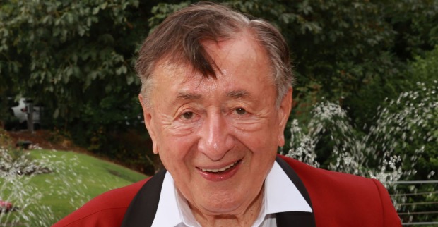 Richard Lugner mit einem roten Anzug und wehenden grauen kurzen Haaren.