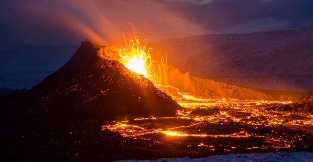Ein isländischer Vulkan bei Nacht, der Asche und Lava spuckt.