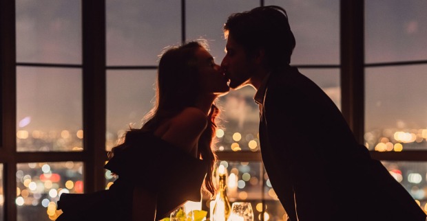 Paar küsst sich bei einem romantischen Dinner | Credit: iStock.com/Prostock-Studio