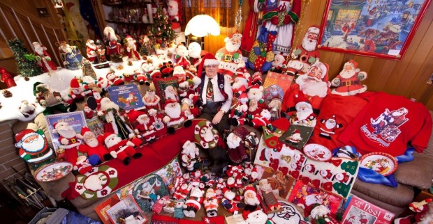 Mann sitzt mitten in seiner Weihnachtsmann-Artikel Sammlung