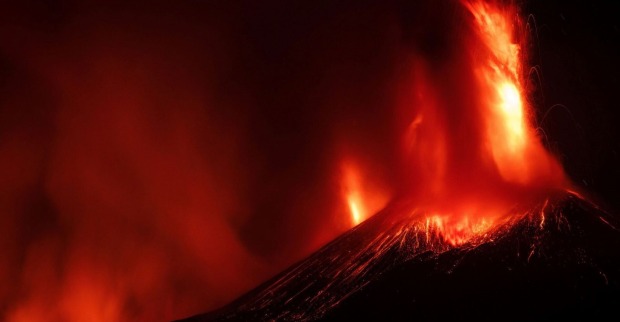 Ausbruch eines Vulkans bei Nacht, Lava schießt in die Höhe.