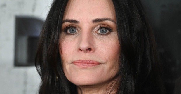 Courtney Cox blickt nachdenklich in die Ferne. Sie hat offene schwarze Haare und dunkel geschminkte Augen.