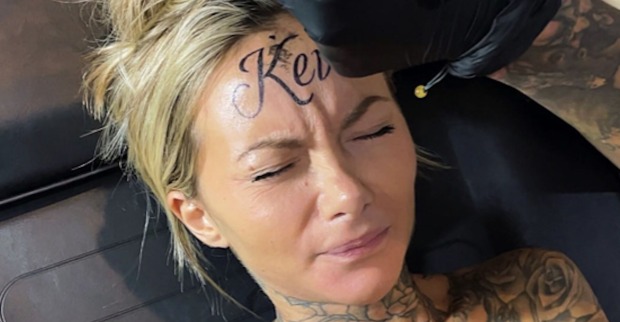 Eine Frau mit blonden Haaren lässt sich "Kevin" auf ihre Stirn tätowieren.
