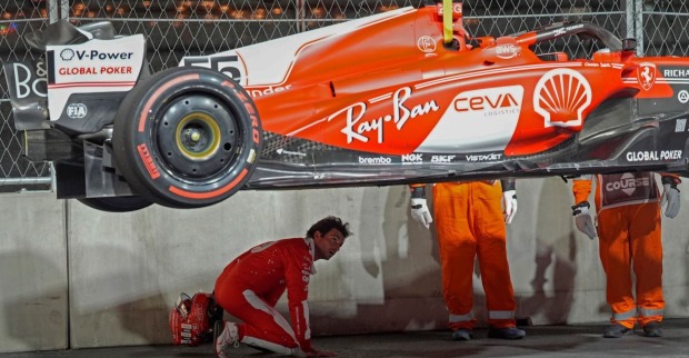 Der desolate Wagen von Ferrari wird von der Strecke gehoben. Mechaniker inspizieren den Unterboden.