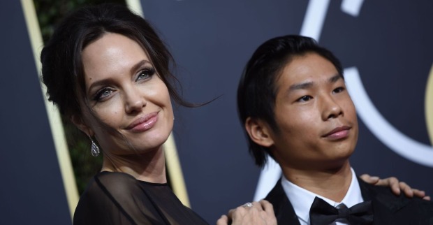 Angelina Jolie trägt hochgesteckt dunkle Haare und ein schwarzes Kleid. Pax trägt einen schwarzen Smoking und ein weißes Hemd.