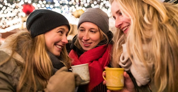 Drei Mädels trinken einen Glühwein am Christkindlmarkt.