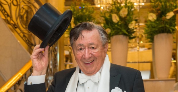 Richard Lugner in der wiener Staatsoper beim Opernball. Er trägt einen schwarzen Anzug und hält einen Hut in die Höhe.
