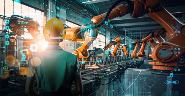 Ein Mann in einer Fabrik mit vielen Robotergreifarmen.