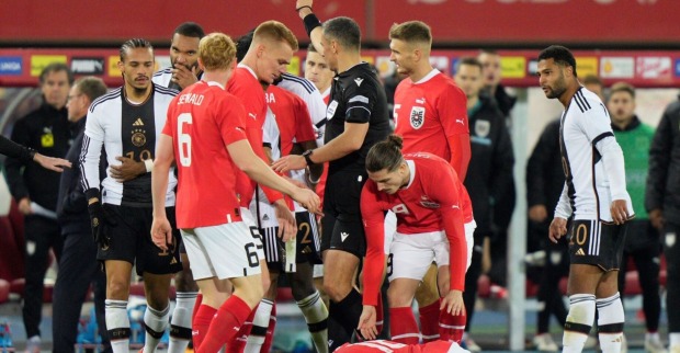 Gemenge deutscher und östererichischer Spieler, ein Österreich liegt am Boden. Der Schiedsrichter zeigt die rote Karte.