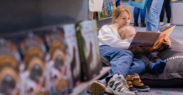 Eine Mutter und ihr kleines Kind haben es sich auf der Buch Wien 23 in einem Sitzsack gemütlich gemacht und schmökern gemeinsam in einem Buch