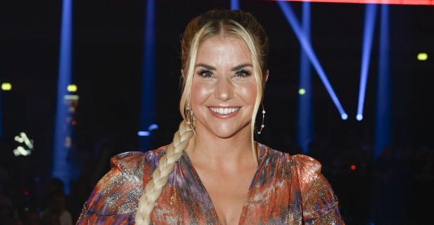 Beatrice Egli mit einem langen blonden Zopf und einer bunten Bluse.