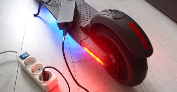 Ein E-Scooter wird an einer Steckdose aufgeladen.