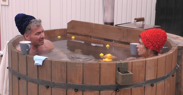 Peter Klein trägt eine schwarze Badehaube. Iris Klein eine rote Badehaube. Beide sitzen ins in einem warmen Whirlpool.