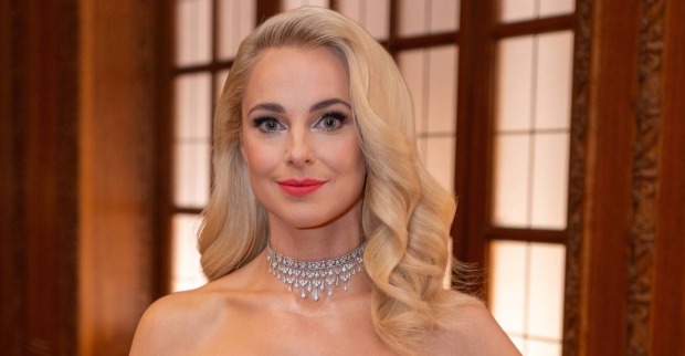 Silvia Schneider hat offene blonde, gewellte Haare und ein Abend-Make-Up. Dazu trägt sie eine Kette aus Diamanten.