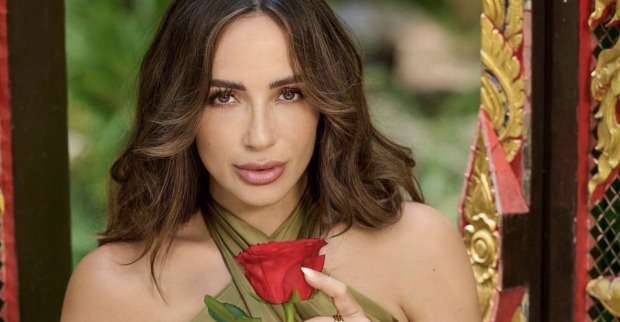 Jennifer Saro mit offenen braunen Haaren und einer Rose in der Hand.
