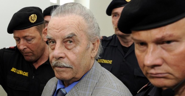 Josef Fritzl zwischen Polizisten am Weg ins Gericht. Er sieht direkt in die Kamera