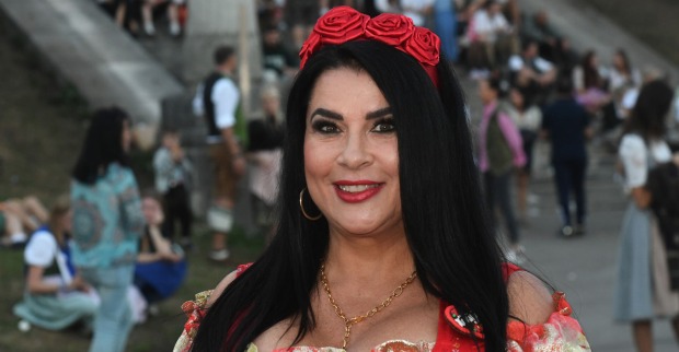 Iris Klein mit einem roten Haarreifen aus Rosen und offenen schwarzen Haaren.