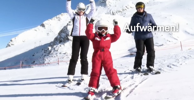 Charlotte zeigt zwei erwachsenen Skifahrerin Aufwärmübungen.