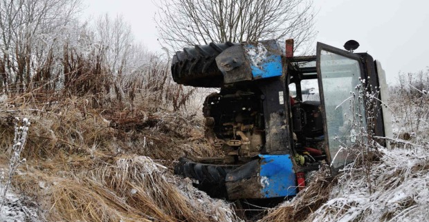 Ein überschlagener Traktor auf einer winterlichen Wiese.