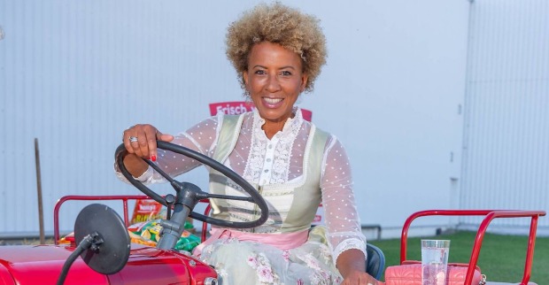 Arabella Kiesbauer im Dirndl auf einem Traktor.