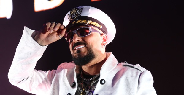 Gigi D'Agostino mit einer weißen Kappe und einer weißen Jacke on stage.