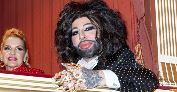 Harald Glööckler mit viel goldenen Schmuck und langen schwarzen Haaren auf dem Opernball 2024.