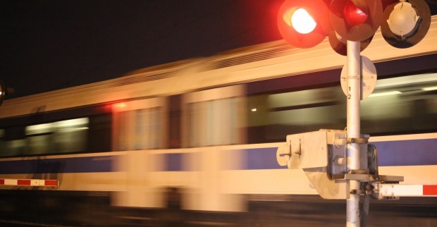 Mit Lichtzeichen geregelter Bahnübergang: Ein Zug braust vorbei.