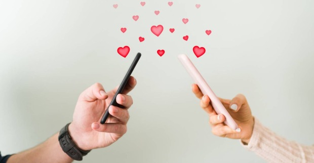 Zwei Personen mit Smartphones, die sich gegenseitig mit Hilfe von Nachrichten Herzenchen schicken