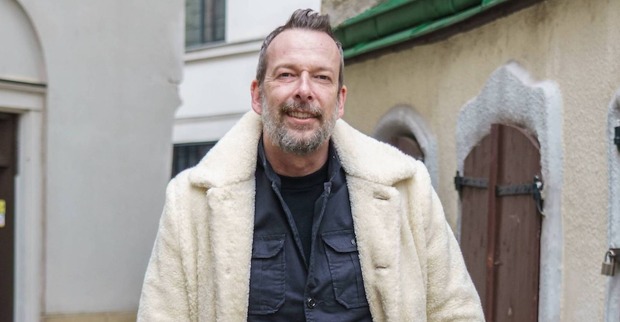 Robert Kratky mit einem weißen Teddy-Mantel in der Innenstadt in Wien-