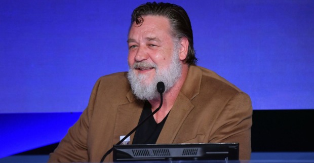 Russell Crowe in einem beigen Sakko bei einem Event. Er trägt einen Vollbart.