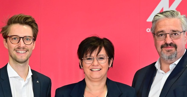 In der Mitte lacht eine Dame mit kurzen braunen Haaren. Ebenfalls lachend: Die Herren links und rechts von ihr, die beiden einen kurzen Vollbart haben und eine Brille tragen. Zu sehen sind links: Gerhard Bremm (Wahlleiter), Andrea Heimberger (AK-Direktorin) und Andreas Stangl (AK-Präsident)-