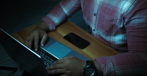 Ein Mann sitzt im Dunkeln vor einem Laptop.