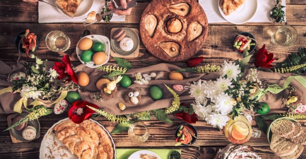 Bunt gedeckter Ostertisch mit traditionellen Speisen, gekochten Eiern und Tischdekoration in Erdtönen