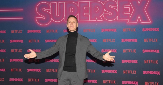 Rocco Siffredi in einem Anzug vor einer Fotowand vom Netflix Film "Supersex"