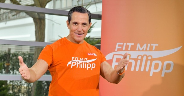 Philipp Jelinek in seine Fitness-Dress vor einem Banner mit der Aufschrift "Fit mit Philipp"