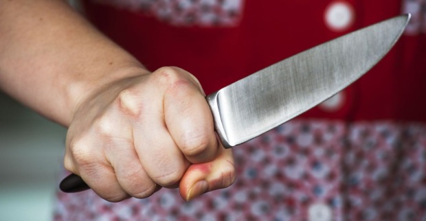 Eine Frau hält ein Küchenmesser bedrohlich in der Hand.