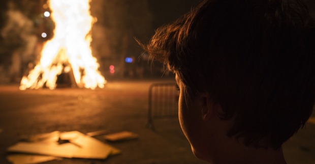 Ein kleiner Bub beobachtet ein großes Feuer.