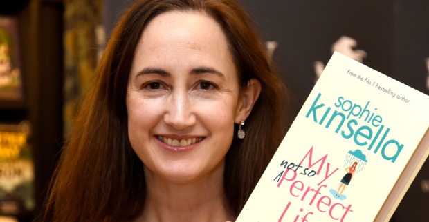 Eine lächelnde Frau hält ein Buch in die Kamera