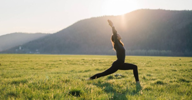 Eine Frau macht Yoga auf einer Wiese.