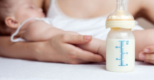 Eine Mutter hält ihr Baby, davor steht das Fläschchen.