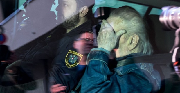 Josef Fritzl in einem Polizeiauto in Polizeibegleitung, er verdeckt sein Gesicht mit der Hand